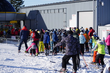 Szczyrk, Poland 15.01.2020: Crowds skiers and snowboarders in a Queue for a comfortable modern chair lift in a mountain resort in winter.