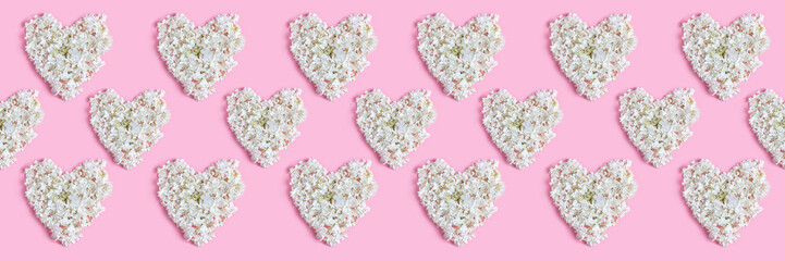 Valentine's day layout. repeating heart pattern of white hydrangea flowers on a pink background. long banner, flat lay, top view