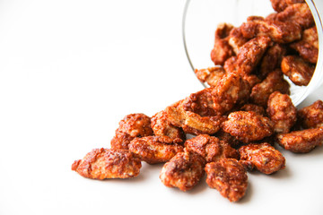 Sugar roasted pecan nuts (caramelized, praline nuts) in a glass on a white background, back view