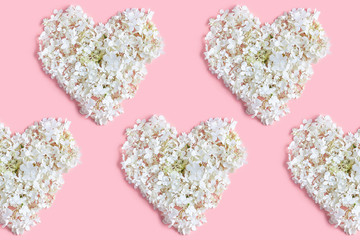 Valentine's day layout. hydrangea flowers are white on a pink background. the pattern in the form of hearts. flat lay, top view