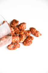 Sugar roasted pecan nuts (caramelized, praline nuts) in a glass on a white background, back view