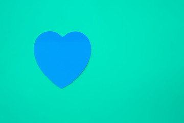 Handmade blue heart on a turquoise panel background