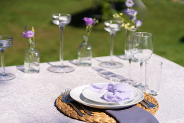 Decorative decoration of the festive table. Glass vases and fresh flowers. Decoration of holidays in the open air