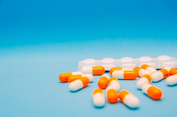 Orange-white capsules and white tablets on a blue background close-up with a copy space