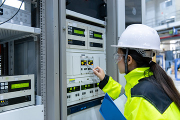 Electrical engineer woman checking voltage at the Power Distribution Cabinet in the control...