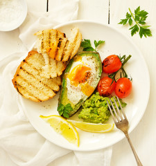 Fried eggs in avocado with guacamole sauce. Breakfast. Selective focus