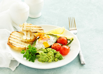 Fried eggs in avocado with guacamole sauce. Breakfast. Selective focus