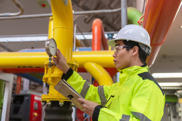 Asian engineer wearing glasses working in the boiler room,maintenance checking technical data of heating system equipment,Thailand people