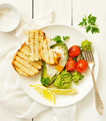 Fried eggs in avocado with guacamole sauce. Breakfast. Selective focus