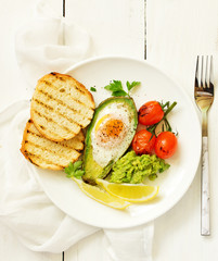 Fototapeta na wymiar Fried eggs in avocado with guacamole sauce. Breakfast. Selective focus