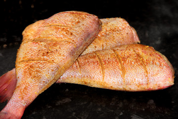 Red perch in a marinade on a black background.