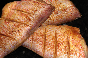Red perch in a marinade on a black background.