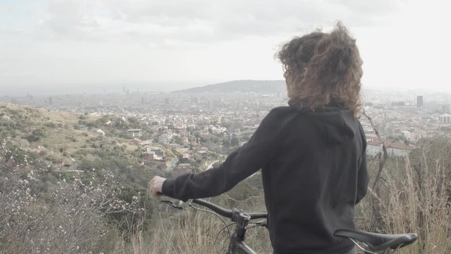 Woman with her bike watching the skyline of Barcelona from the mountain