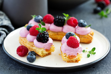 Homemade eclair with berry cream and fruits. . Pastry.