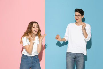 Shocked, astonished crazy. Young and happy man and woman in casual clothes on pink, blue bicolored background. Concept of human emotions, facial expession, relations, ad. Beautiful caucasian couple.
