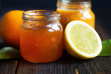 citrus jam with lemon and tangerine in glass jar on wooden table