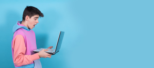 young teenage man or student with laptop isolated on background with surprise or success expression