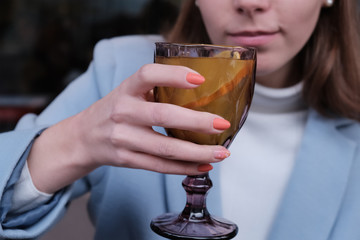 Woman drink hot orange tea in coat.