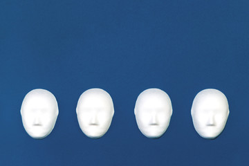 Four white blank identical faceless mockup heads on blue background. Flat lay with copy space....