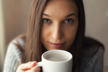 Beautiful girl on a winter morning drinking coffee, close-up.
