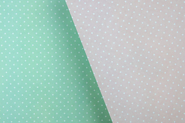 Colored paper background. delicate pastel color, mint green and pink in white polka dots. diagonally, with a shadow
