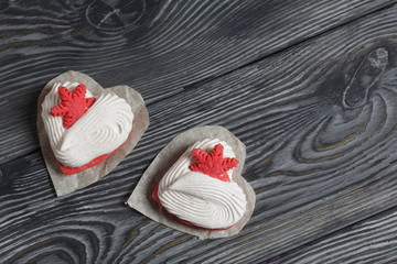Marshmallow sandwiches decorated with cookies in the shape of a snowflake. On brushed pine boards painted in black and white. View from above.