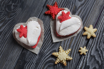 Marshmallow sandwiches decorated with cookies in the shape of a snowflake. On brushed pine boards painted in black and white.
