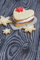 Marshmallow sandwiches decorated with cookies in the shape of a snowflake. On brushed pine boards painted in black and white.