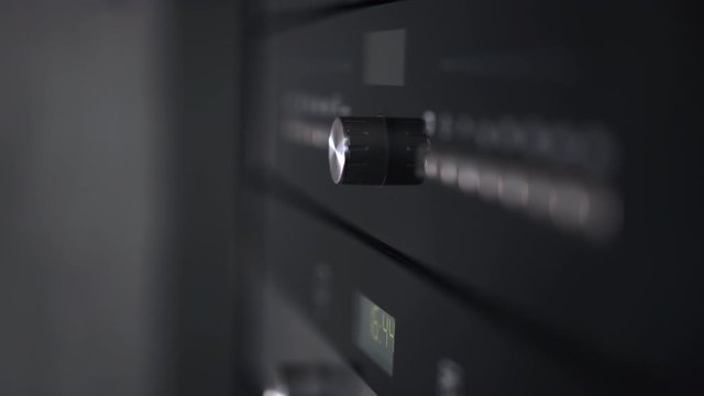 Female hand twist knob of handle on modern gas stove. Woman turning temperature on oven button . Closeup view.