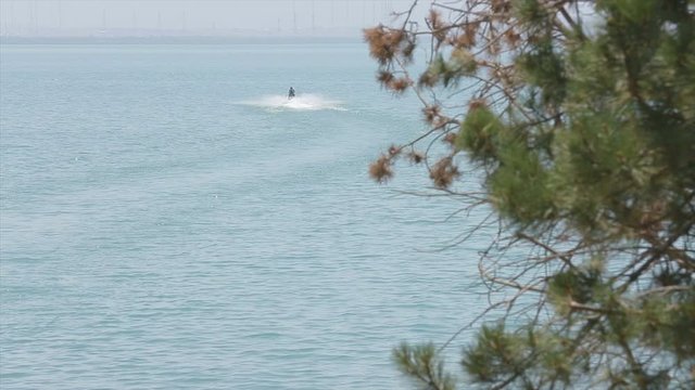 Riding a scooter in Lake Sevan (Armenia). Tricks with a scooter in the water. Beautiful footage of the beach and trees. Shoot on 10 August 2019.