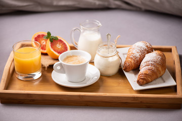 Continental breakfast. Breakfast tray on bed with coffee, orange juice and croissant
