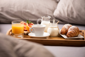 Continental breakfast. Breakfast tray on bed with coffee, orange juice and croissant