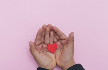 child holding red heart on light background, top view