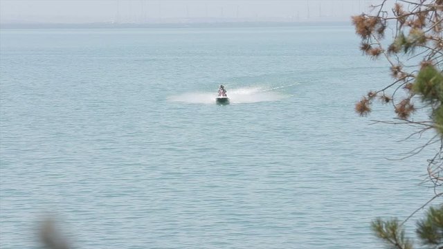 Riding a scooter in Lake Sevan (Armenia). Tricks with a scooter in the water. Beautiful footage of the beach and trees. Shoot on 10 August 2019.