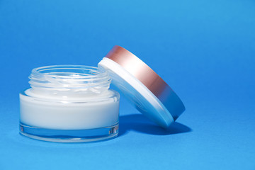 white cosmetic cream in a jar on a blue background