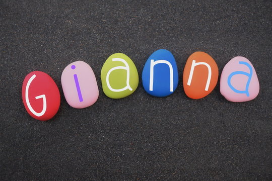 Gianna, female given name composed with multi colored stone letters over black volcanic sand