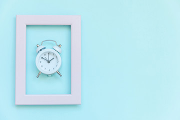 Ringing twin bell vintage alarm clock in pink frame isolated on blue pastel colorful trendy background. Rest hours time of life good morning night wake up awake concept. Flat lay top view copy space