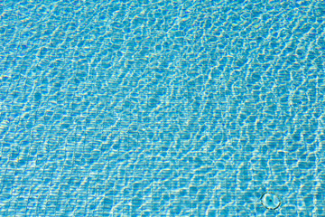 Blue swimming pool reflecting the sun rippled