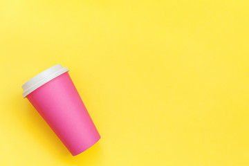 Simply flat lay design pink paper coffee cup isolated on yellow colorful trendy background. Takeaway drink container. Good morning wake up awake concept. Template of drink mockup. Top view copy space