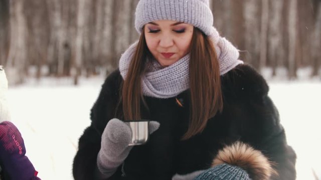 A young woman drinking hot drinks with her family - gives her little son a cup