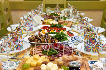 Beautiful served table for wedding or other celebration in restaurant with dishes of cheese, sausage, vegetables (eggplant, tomatoes, bell pepper)