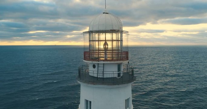 Picturesque white lighthouse at the sunset. 4k footage. Aerial view.