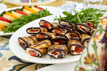 Rolls of fried eggplant with mayonnaise garlic sauce and tomato, close-up