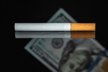 Money and Cigarette. Cigarette and dollar. smoking is an expensive habit. financial cost of smoking.