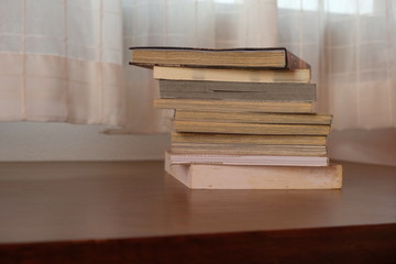 Close up of stack or pile of old book that place on a table near to the window