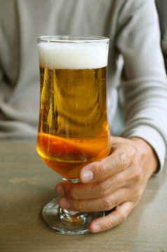 Vertical image of a man holding glass of lager beer