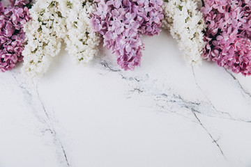 Floral pattern of a branch of lilac on a trendy marble background. Top view. Flat lay. Spring concept. Copy space
