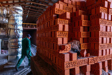 Production of clay bricks at a brick factory. Ready hot red bricks stacked on pallets cools after...
