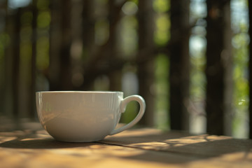A cup of coffee on a wooden table in the morning. With copy space. and sunlight naturally a blurred background.