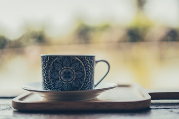  A beautiful cup of coffee on a wooden table in the morning. and a blurred background. and vintage